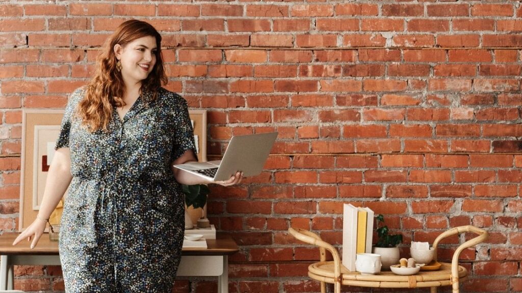 woman holding a laptop in front of a brick wall making a national nutrition month presentation