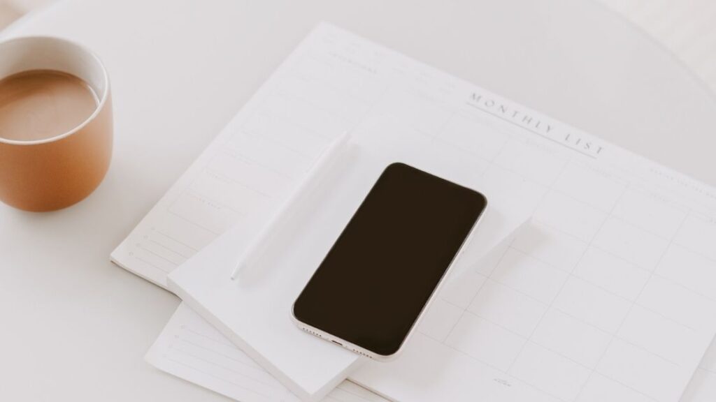a cell phone on top of a monthly planner on a desk