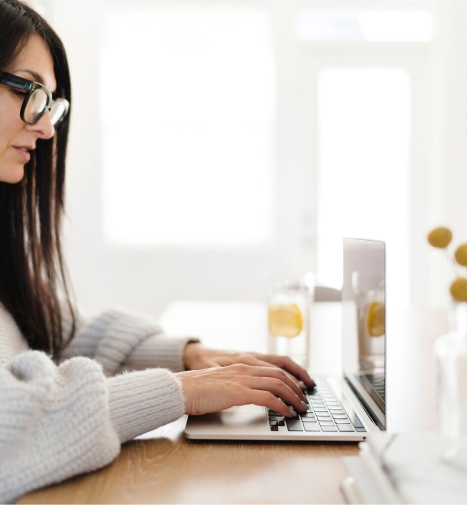 A dietitian in a white sweater typing on a laptop