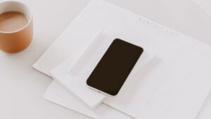 a cell phone on top of a monthly planner on a desk