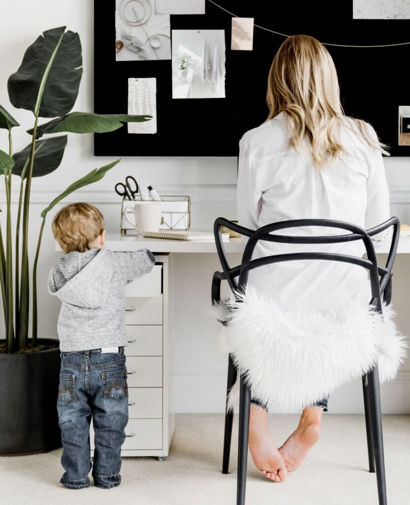 Mom working at desk with son exploring the drawers